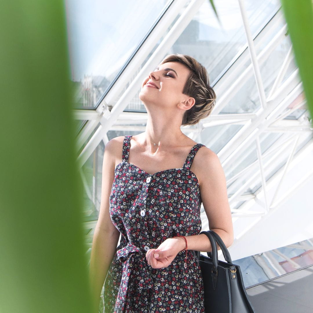 Traveler walking through an airport terminal corridor taking a deep breath amid lush greenery.